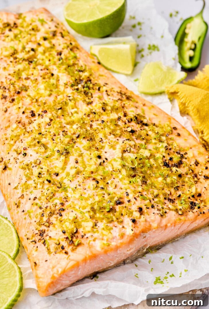 A plated serving of Oven Baked Salmon with lime slices and jalapeño rings, presented beautifully.