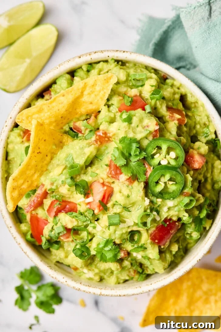 Top-down view of a bowl of guacamole surrounded by tortilla chips, ready to serve.