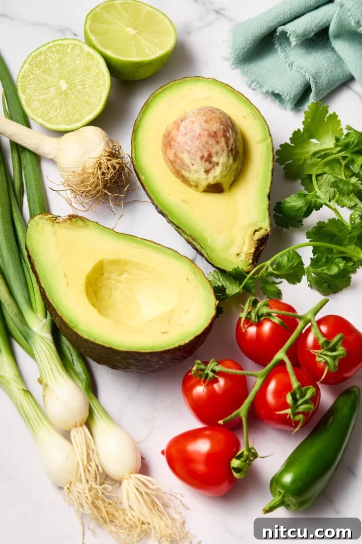All the fresh ingredients for guacamole laid out on a kitchen counter.