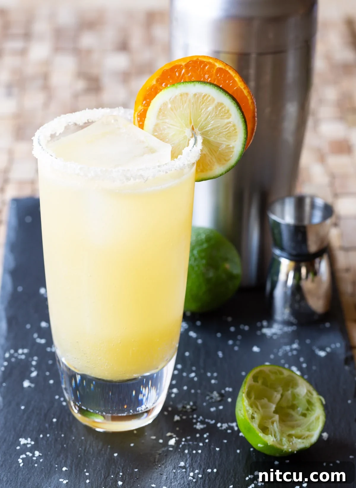 A refreshing margarita in a cocktail glass with a salted rim and fresh citrus garnishes.