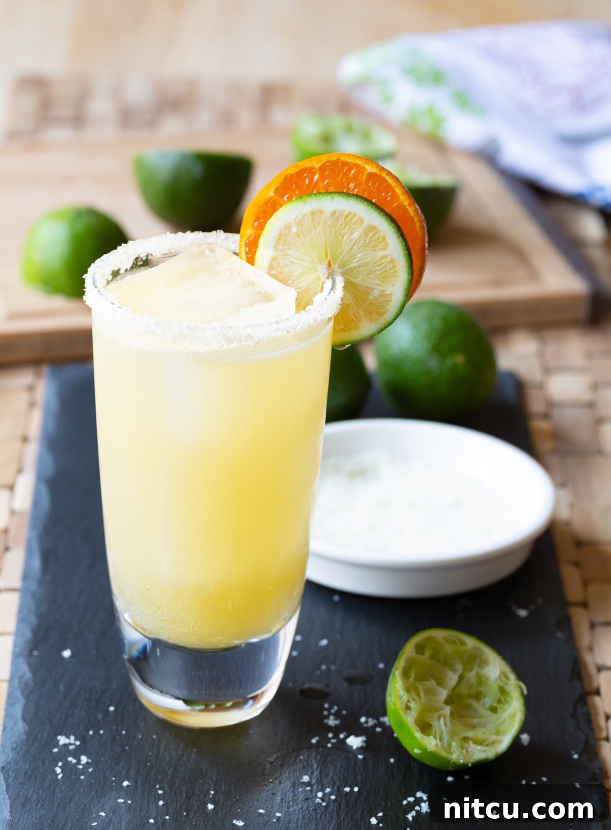 A meticulously prepared margarita served in a glass with a perfectly salted rim and fresh citrus garnishes.