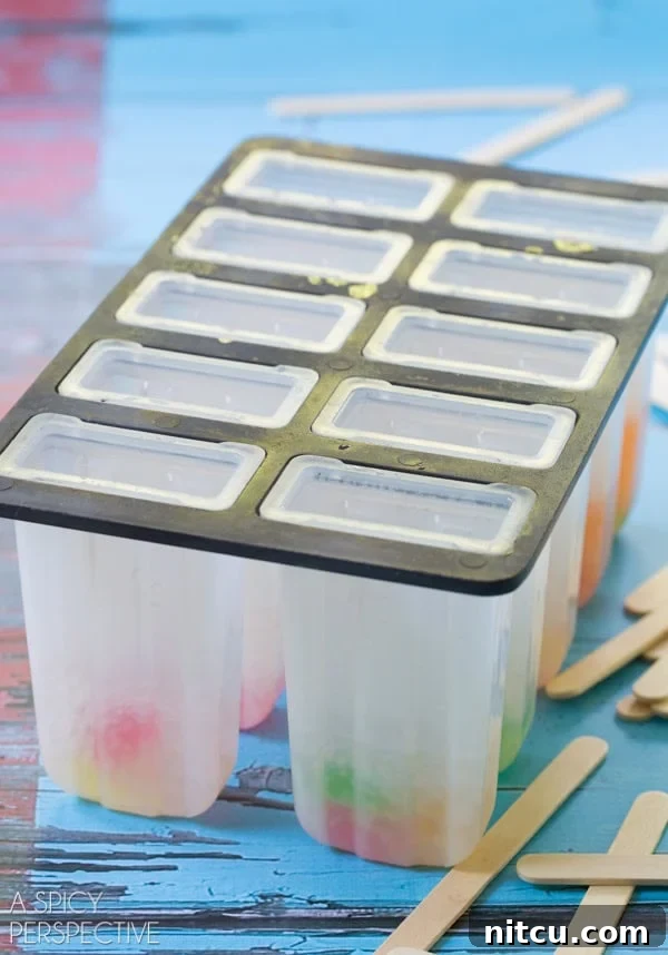 Popsicle molds with the first layer of vodka gummy bears and soda