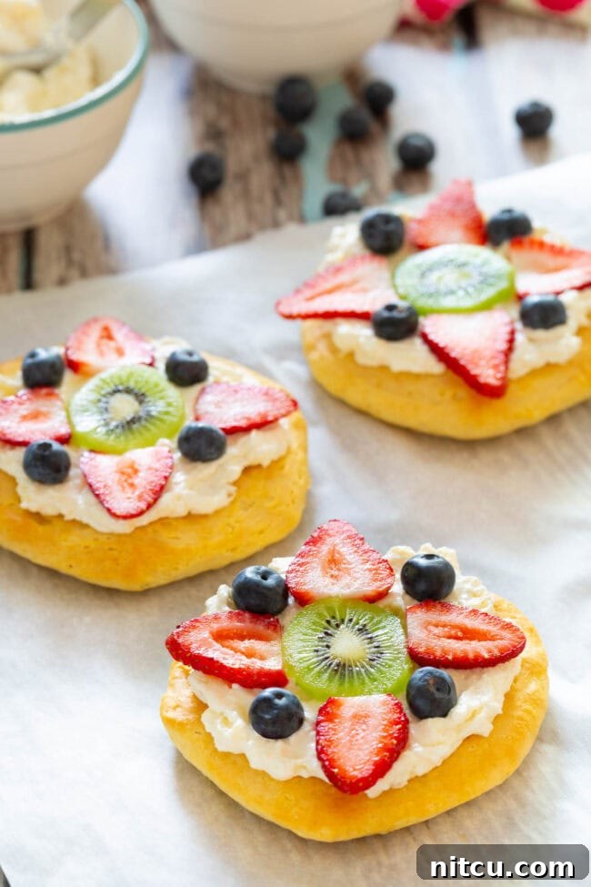 Close-up shot of a breakfast fruit pizza on a baking sheet, topped with colorful berries, ready to serve.