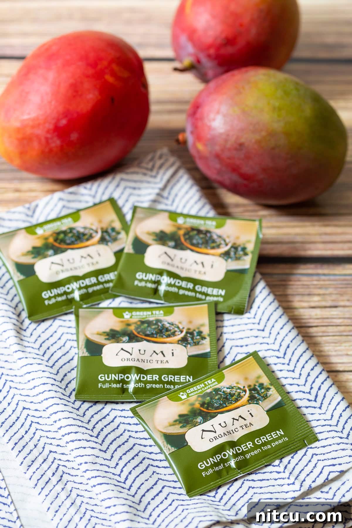 Several green tea bags arranged neatly on a white and blue patterned towel, highlighting the primary energy-boosting ingredient for the smoothie.