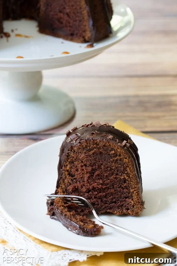 A delicious slice of Baileys Irish Cream Bundt Cake, beautifully presented on a plate with a fork, showing off its perfect texture and rich toppings.