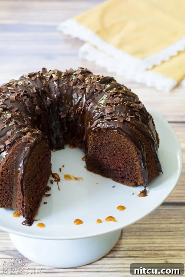 A plated slice of Baileys Irish Cream Bundt Cake, showcasing its moist interior and generous toppings, with a piece already enjoyed.