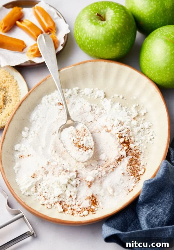 Flour and spice mixture for baked mini apple pies in white bowl.