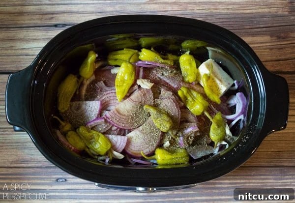 Close-up of ingredients for Slow Cooker Italian Beef Recipe including beef, onions, and pepperoncinis