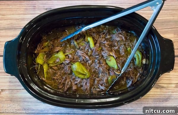 Italian Beef cooking in a slow cooker, showing tender meat in savory broth