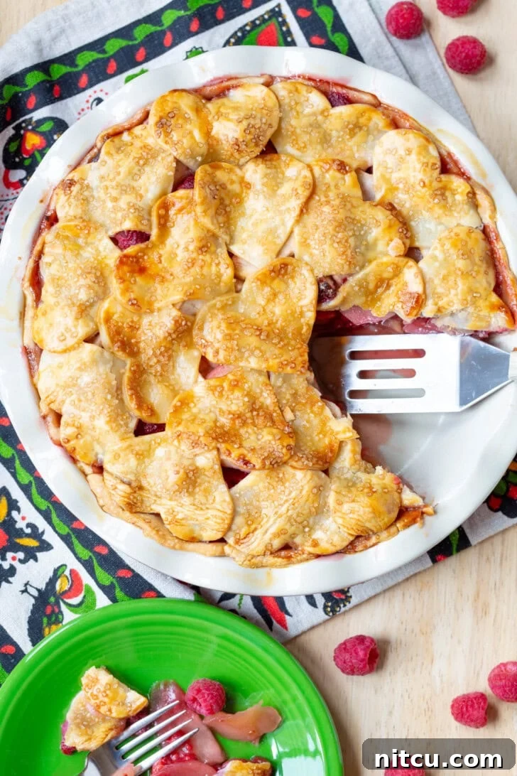 Delectable Raspberry Apple Pie with a slice removed, showcasing the vibrant fruit filling.
