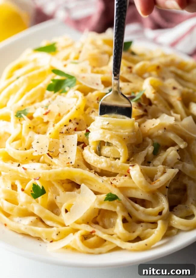 Close-up of creamy Alfredo sauce with fresh fettuccine pasta being tossed