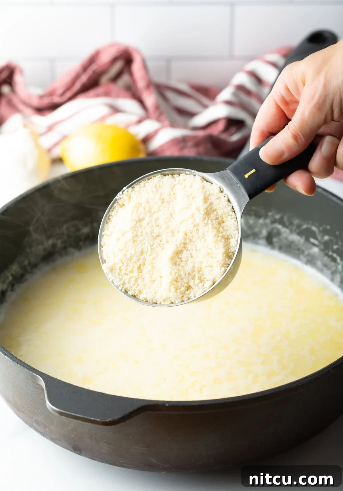 Mixing freshly grated Parmesan cheese into the creamy Alfredo sauce base