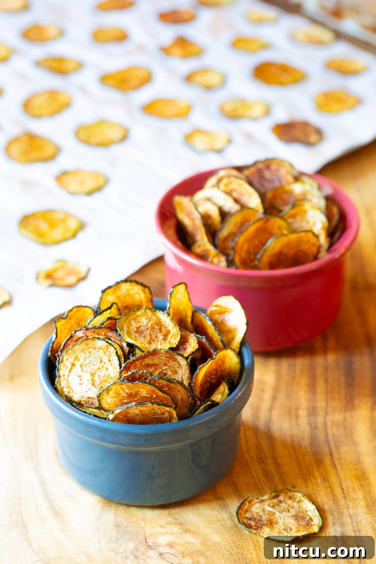 Baked zucchini chips from scratch served in two small ramekins. 