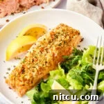 Parmesan crusted salmon, baked to a golden crisp with a few bites taken, showcasing its delicious texture.