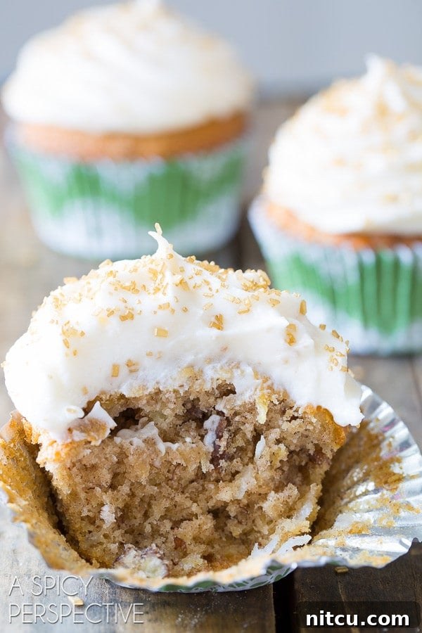 Close up of a half-eaten Hummingbird cupcake, showing the soft, moist interior and generous frosting.