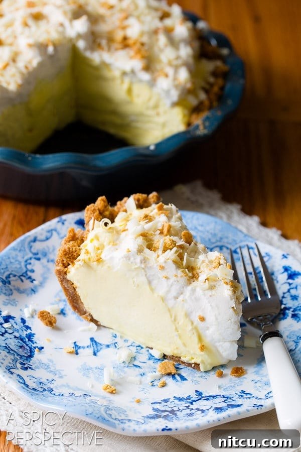 Slice of silky lemon cream pie on a plate with a fork.