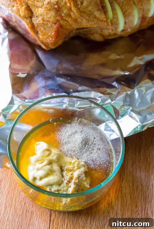 A close-up of the honey mustard glaze being brushed onto the spiral ham before baking.