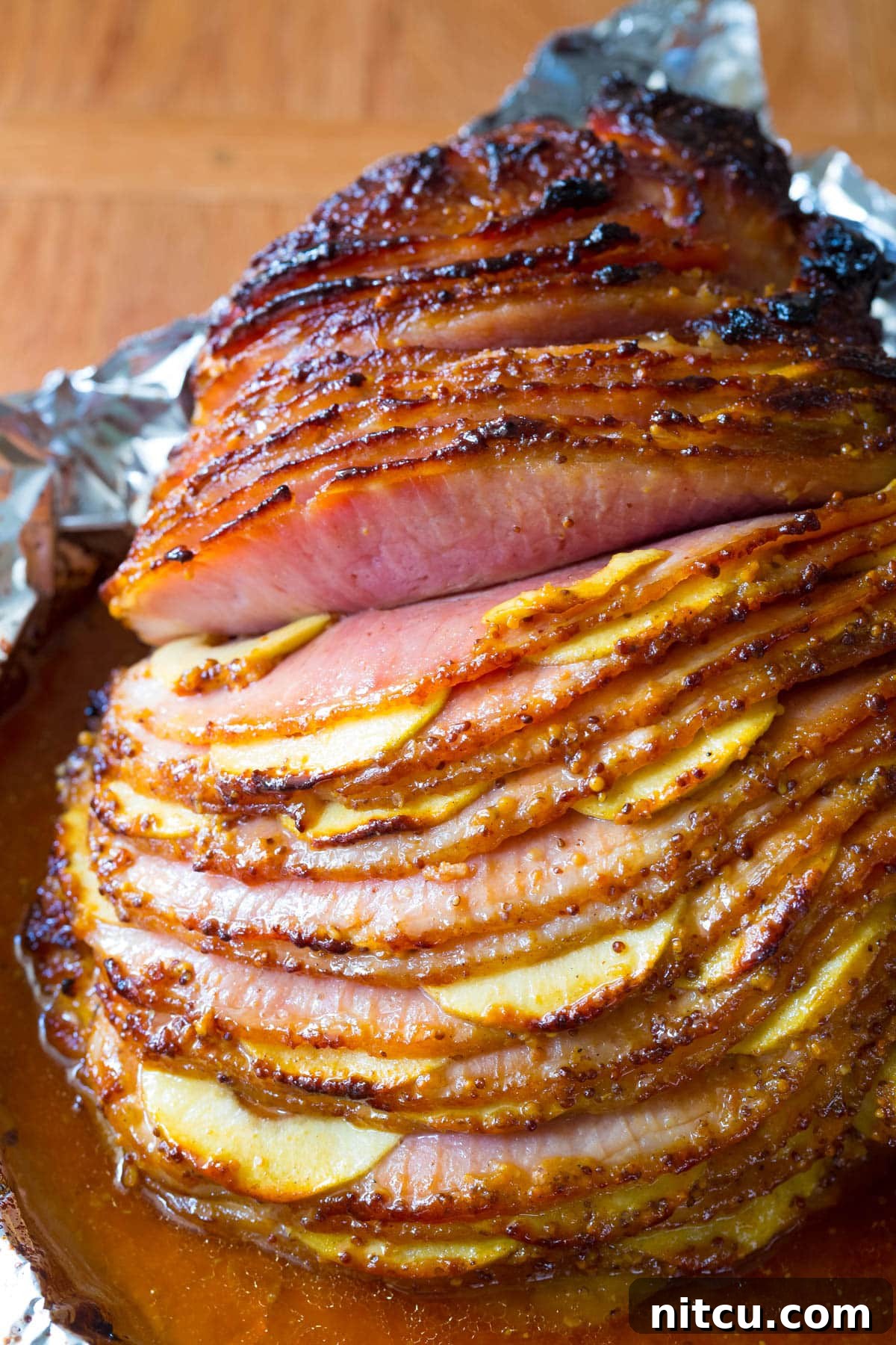 A close-up view of the perfectly cooked, juicy ham stuffed with apples, showcasing its tender texture and golden glaze.