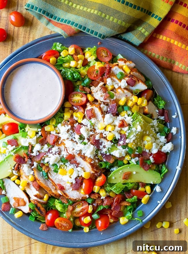 Overhead shot of grilled chicken salad with a side of dressing. 