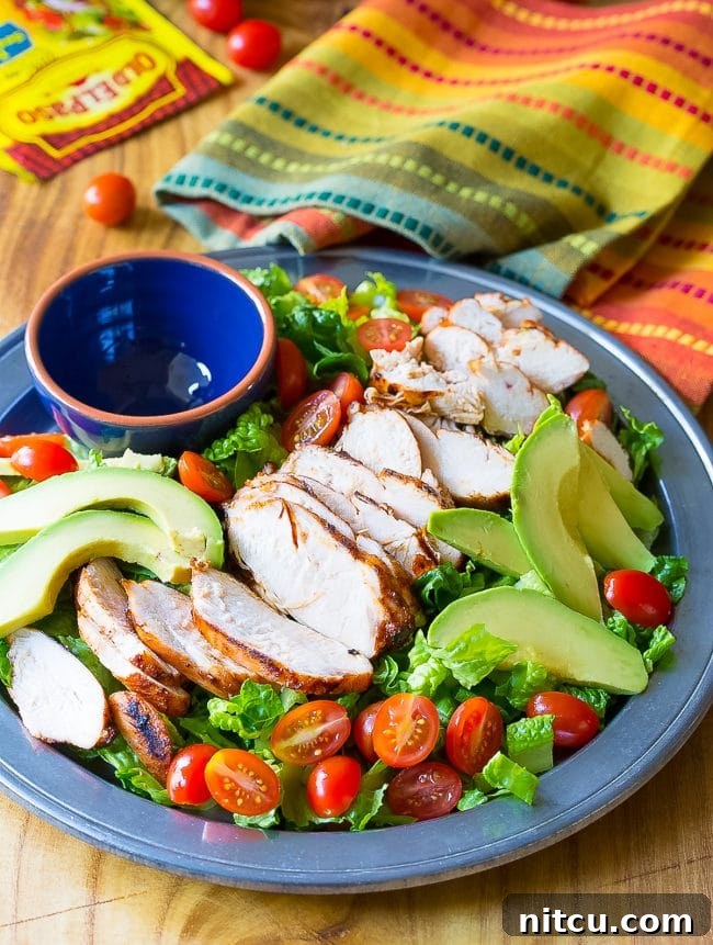 Loaded Mexican grilled chicken salad on a platter with an empty ramekin.