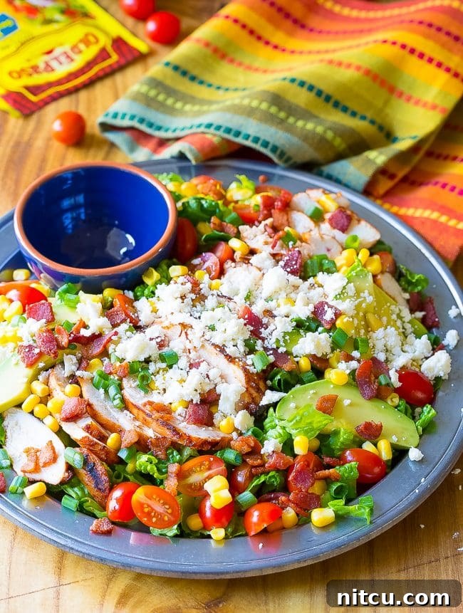 Mexican Chicken Salad with chicken, bacon, corn, tomatoes, avocado and queso fresco on a large plate. 