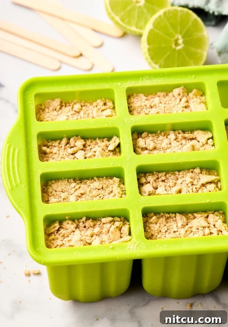 5-Ingredient Key Lime Pudding Popsicles - in molds with graham cracker garnish on top.