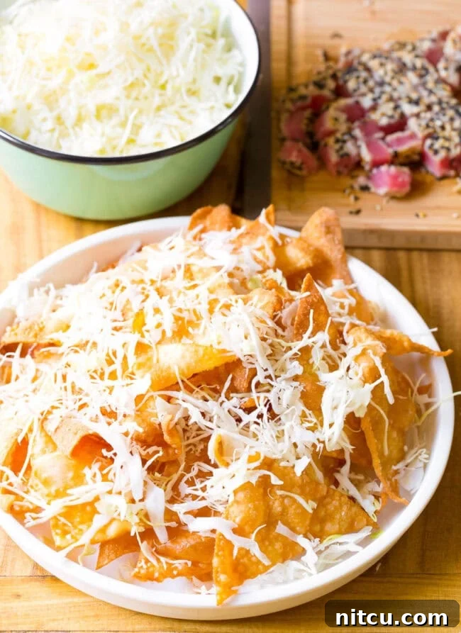 Wonton chips on a white plate topped with shredded cabbage.