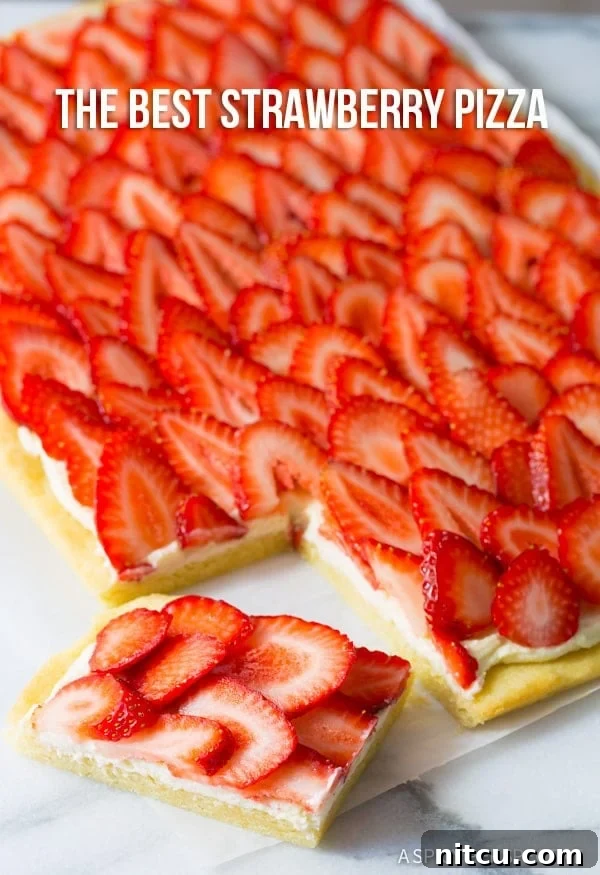 A slice of strawberry dessert pizza, showcasing the layers of cookie, goat cheese, and fresh fruit.