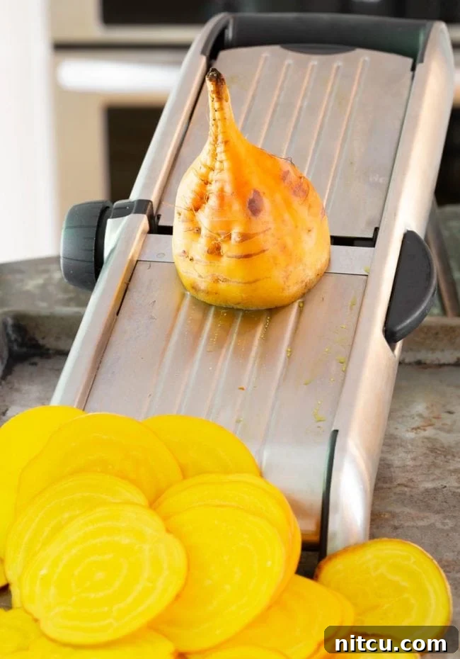 Beets being sliced on a mandoline slicer. Achieving uniform thinness.