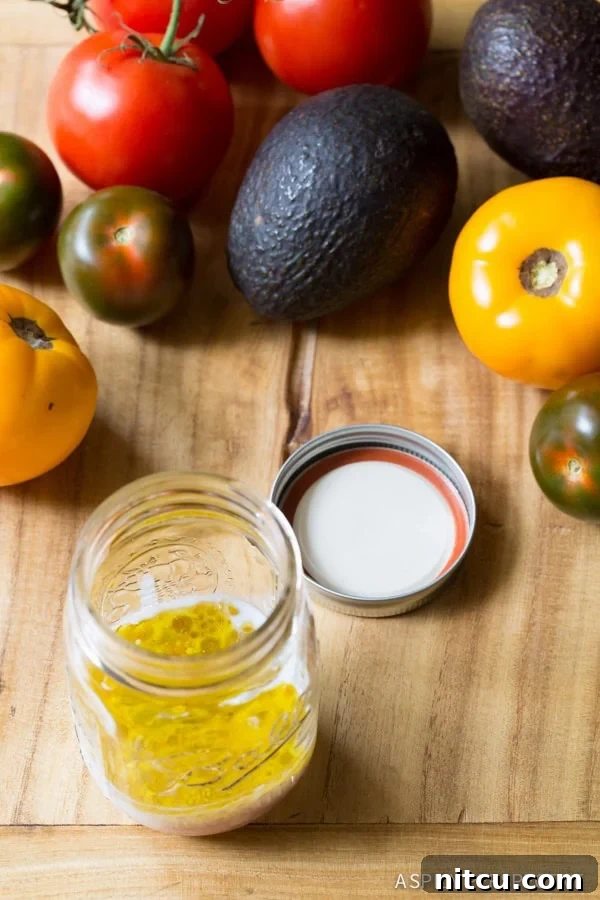 A rustic wooden cutting board adorned with a colorful array of fresh produce, including large, ripe tomatoes and creamy avocados. In the foreground, a clear mason jar filled with a golden, liquid dressing hints at the vibrant flavors of the A1 vinaigrette.