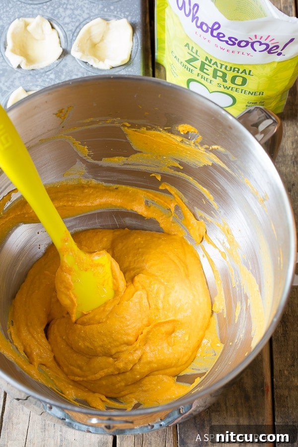 Detailed shot of the steps involved in making the best mini pumpkin pies. Filling the puff pastry shells.