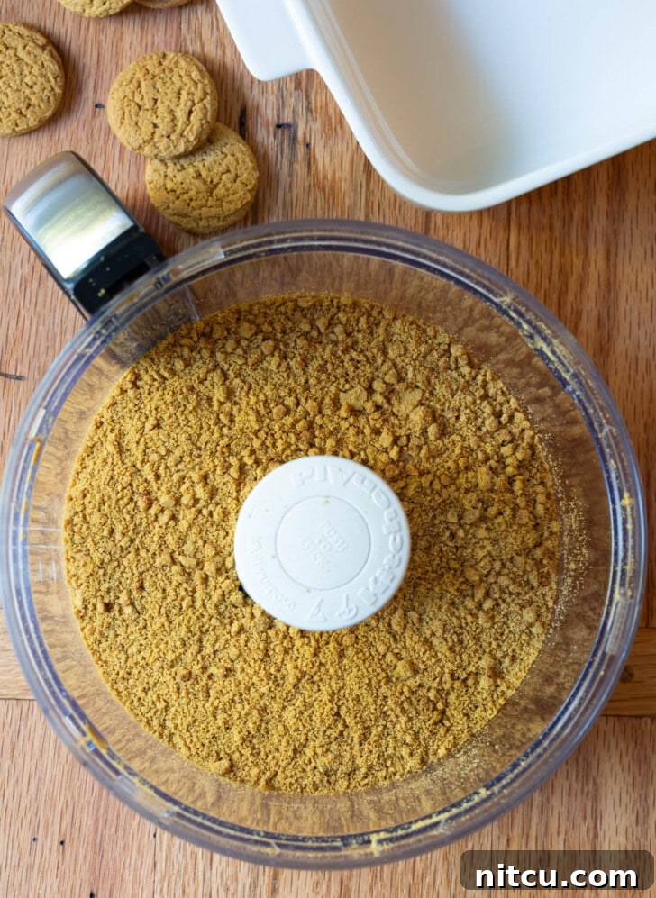 Gingersnap crumbs, sugar, and melted butter combining in a food processor for the crust.