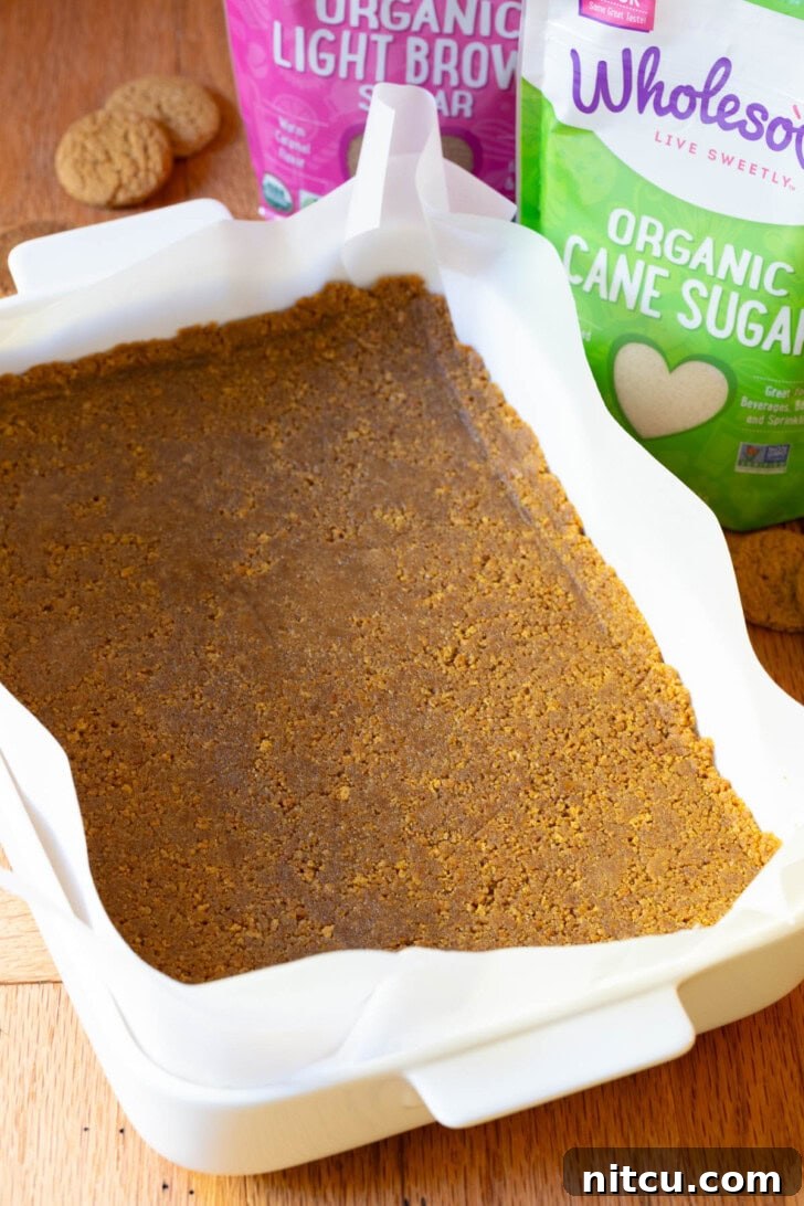 Smooth cheesecake batter being spread evenly over the gingersnap crust.
