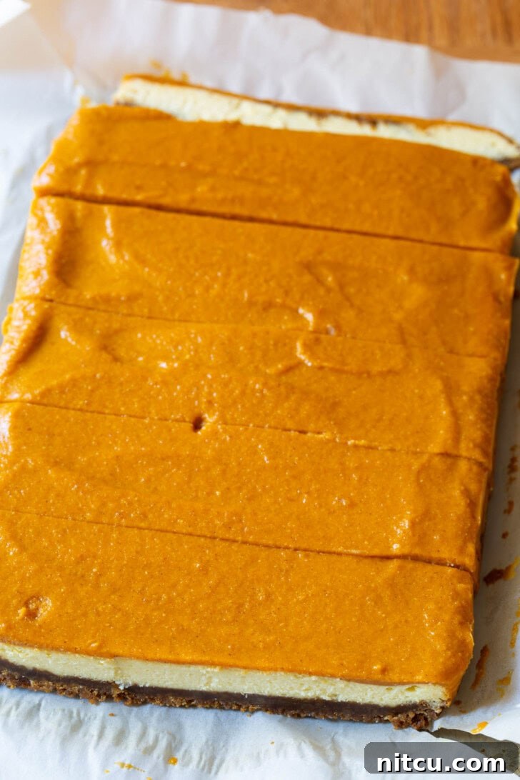 A sheet of pumpkin cheesecake bars being carefully sliced into individual servings.
