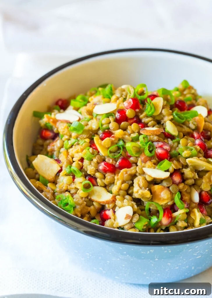 Lentil salad with pomegranate, almonds and scallions in a serving bowl. 