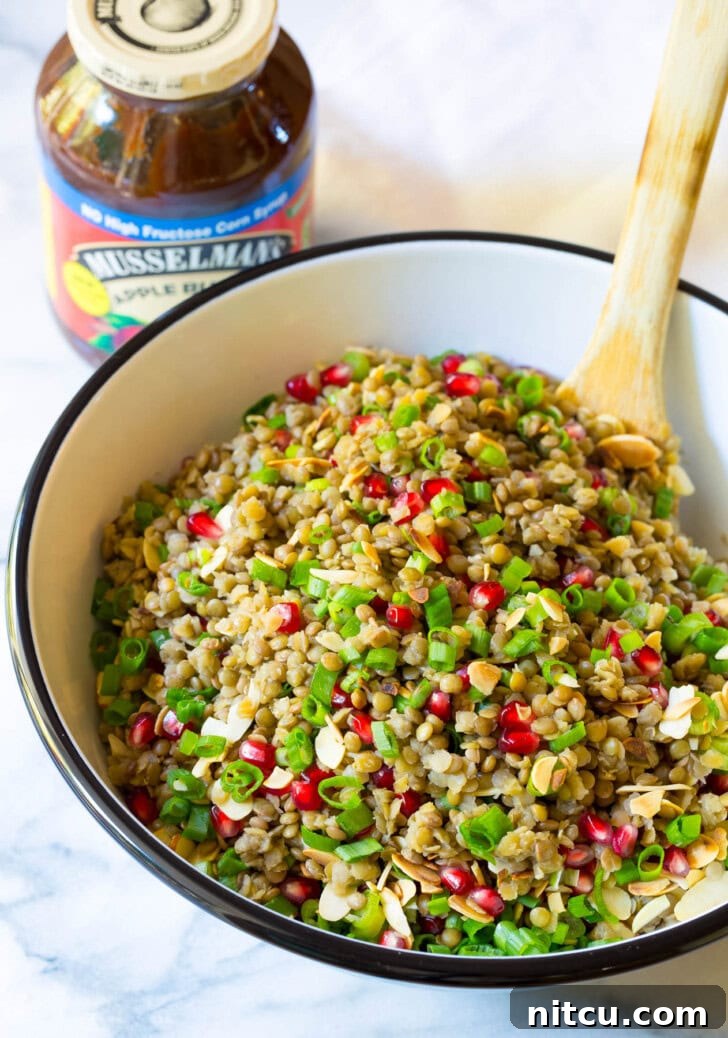 Healthy Lentil Salad with Apple Cider Vinaigrette in a large serving bowl with a wooden spoon. 