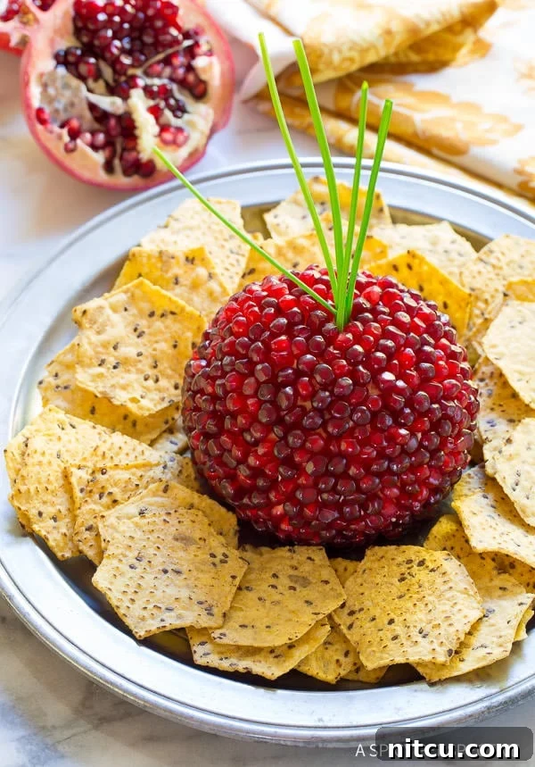Pomegranate Cheese Ball on platter with crackers and scallion garnish