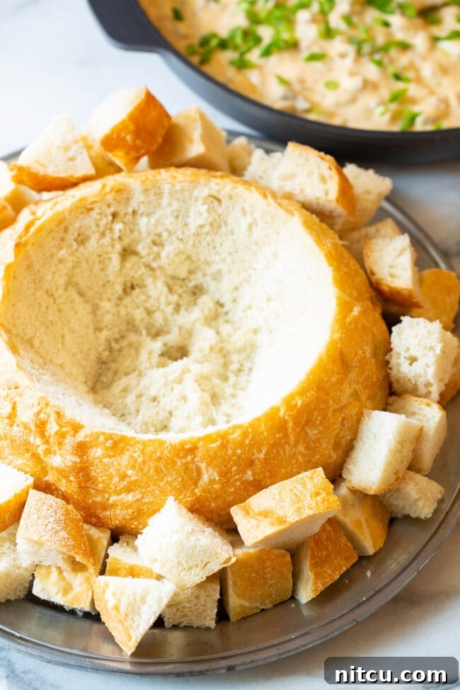 A rustic, hollowed-out sourdough bread loaf, perfectly prepared as a bowl, resting on a wooden surface before being filled with dip.