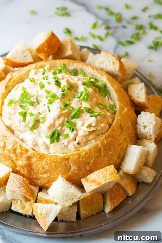 Another inviting image of the creamy sausage cheese dip served in a sourdough bread bowl, artfully arranged on a platter with various dippers, ready for a festive gathering.