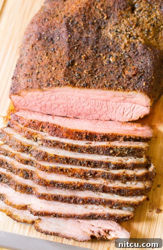 Sliced beef brisket (oven recipe) on a wooden cutting board.
