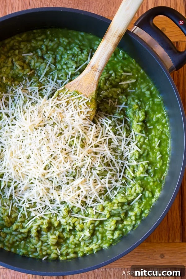 Overhead shot of Vibrant Herbaceous Green Risotto topped with shredded parmesan in a saucepan.