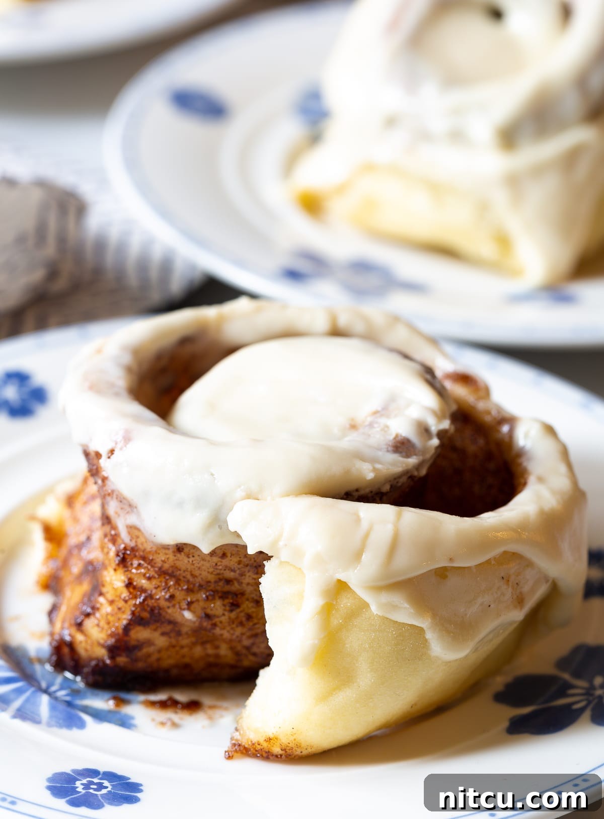 A baked cinnamon roll on a plate with its soft, spiraled layers gently untwisted, showing the rich cinnamon filling.