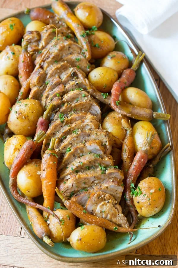 Sliced slow cooker pork tenderloin on a plate with vegetables