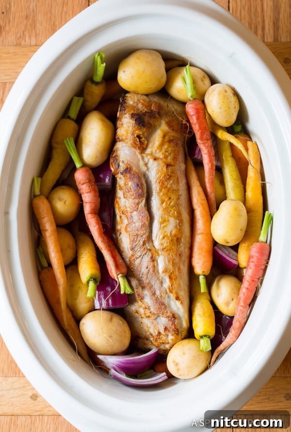Pork tenderloin and carrots placed in a crockpot before slow cooking