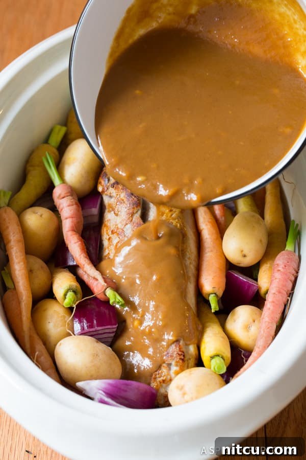 Crock Pot Pork Loin with Vegetables on a platter, covered with rich gravy