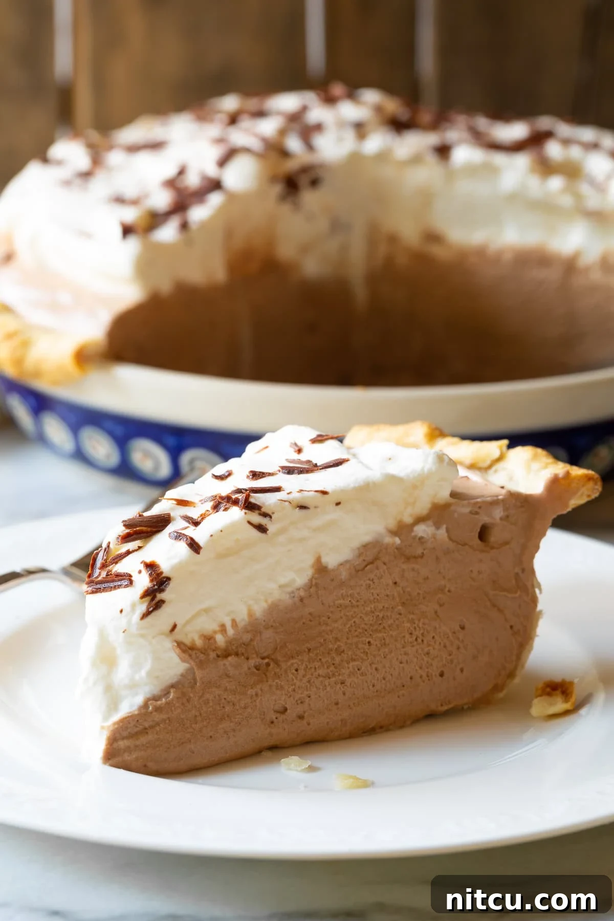 Close-up of a slice of French Silk Pie on a plate, showing its silky texture and whipped cream.