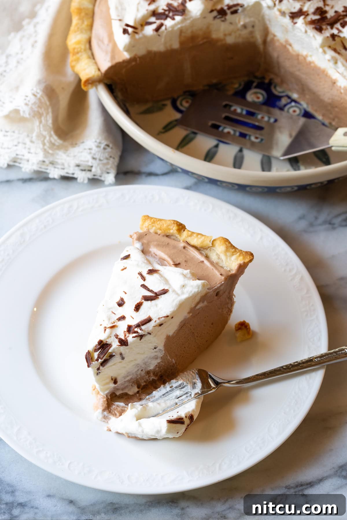 A single slice of chocolate cream pie, showcasing its perfect layers and smooth texture.