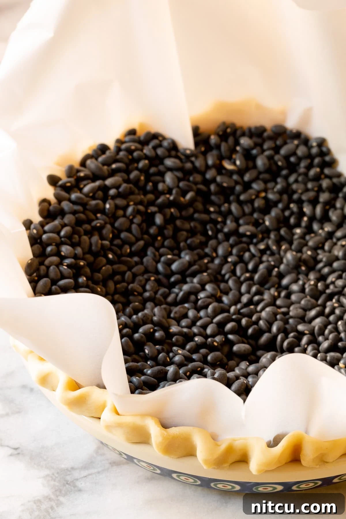 Unbaked pie crust in a pan, weighted down with beans for blind baking.