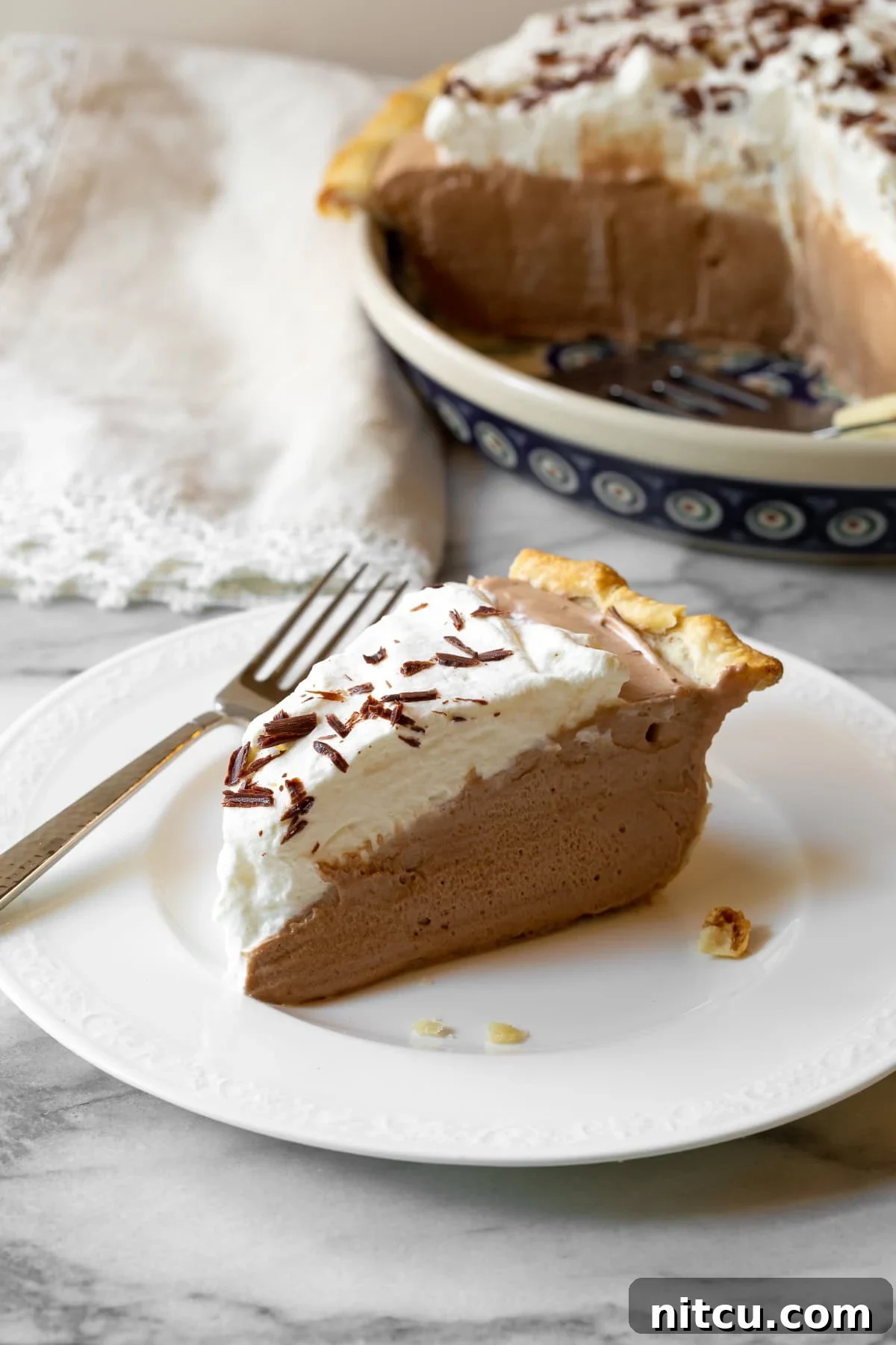 A slice of French Silk Pie on a plate, with a fork poised to take a bite, highlighting its creamy texture.