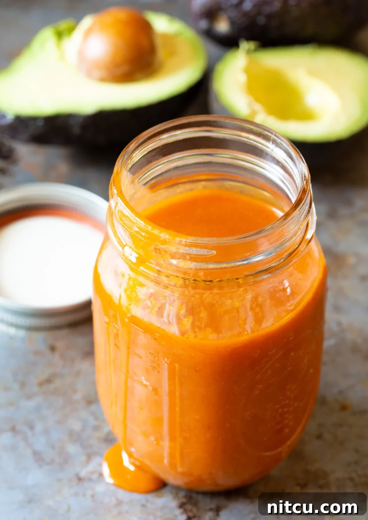 Catalina dressing in a mason jar with avocados in the background.